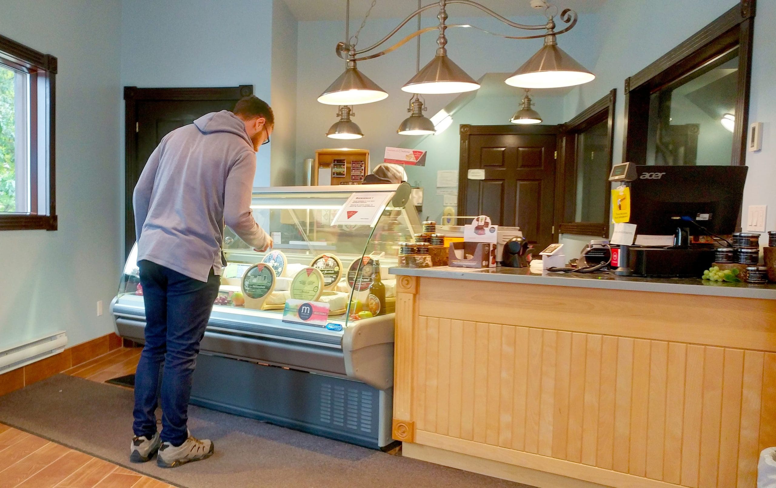 Un homme observant les fromages au comptoir de la fromagerie Du Champ à la Meule